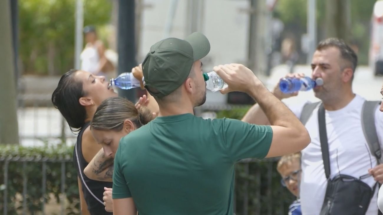 Un grupo de personas beben agua en una calle de Madrid