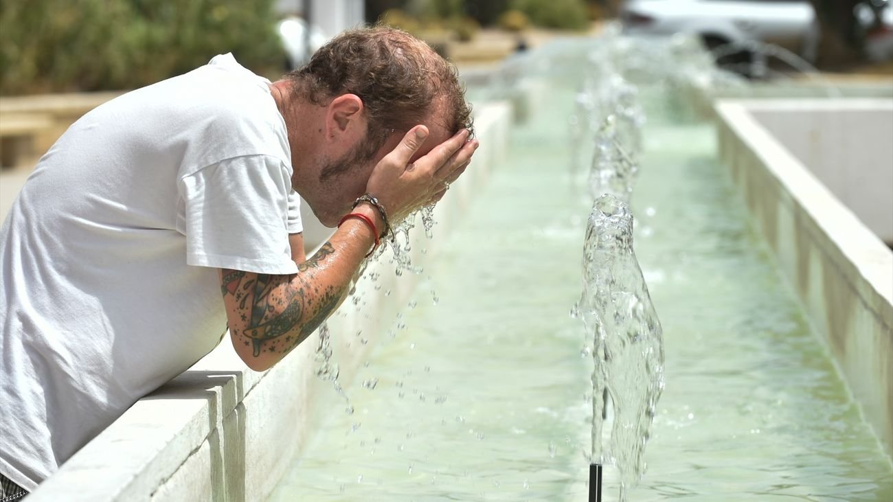Un hombre se refresca en una fuente durante una ola de calor